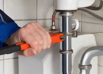 Plumber tightening a sink drain connection in Shreveport, LA.