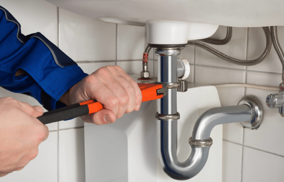 Plumber tightening a sink drain connection in Shreveport, LA.