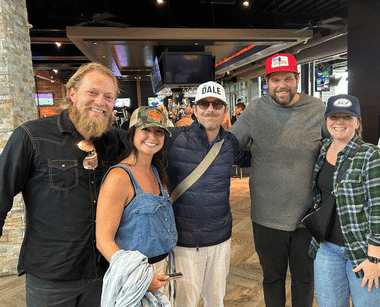 Group of five people smiling together at an indoor venue