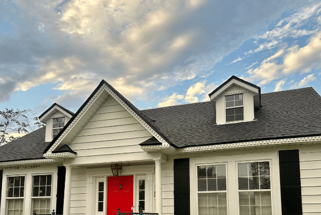 White two-story home with a dark shingle roof and red front door