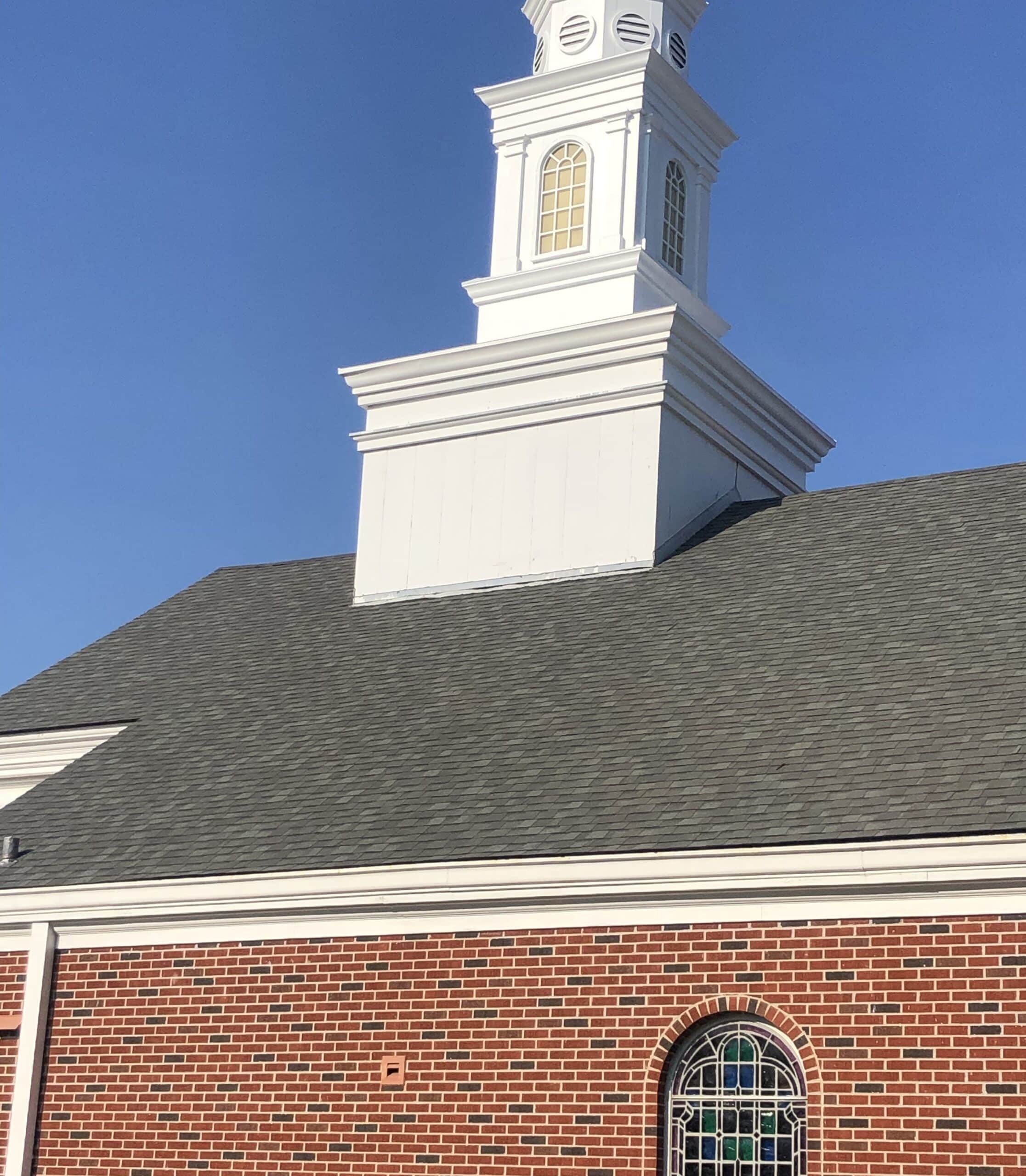 New shingle roof on a brick church with a white steeple, a commercial roofing project by Blue Note Pros in Shreveport