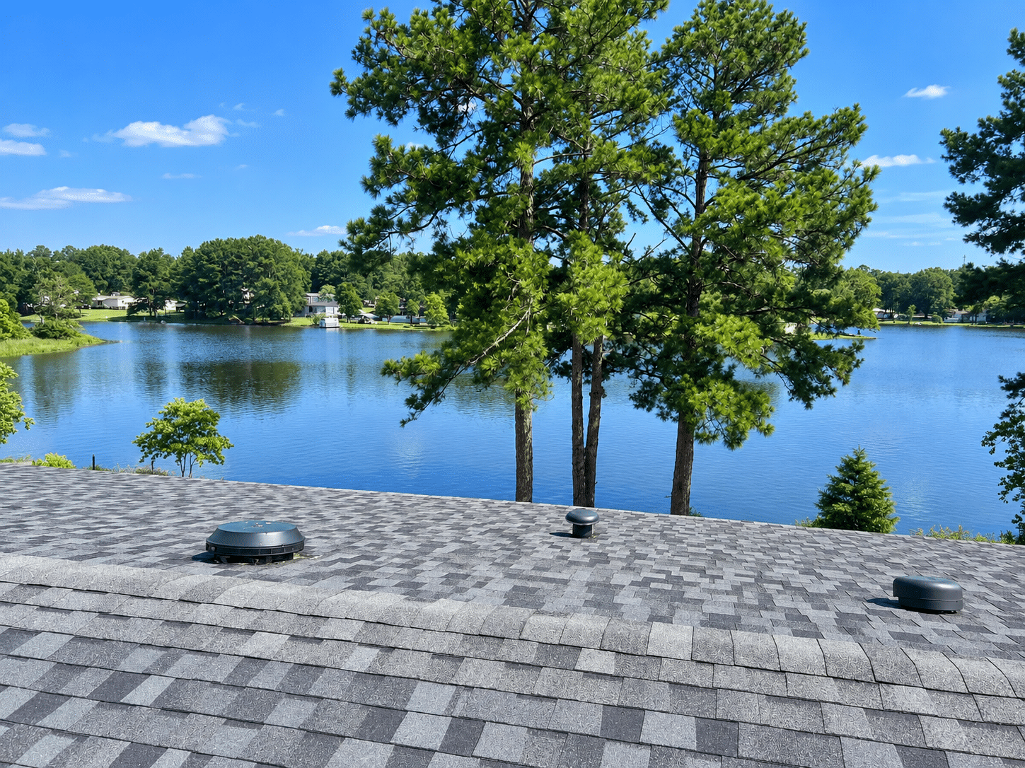 Turtle vents on an asphalt shingle roof overlooking a lake, roof accessories Blue Note Pros checks for gaps after Shreveport storms