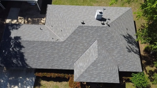 Drone view of a complex multi-hip shingle roof, where roof size, pitch, and layout affect roof repair costs in Shreveport