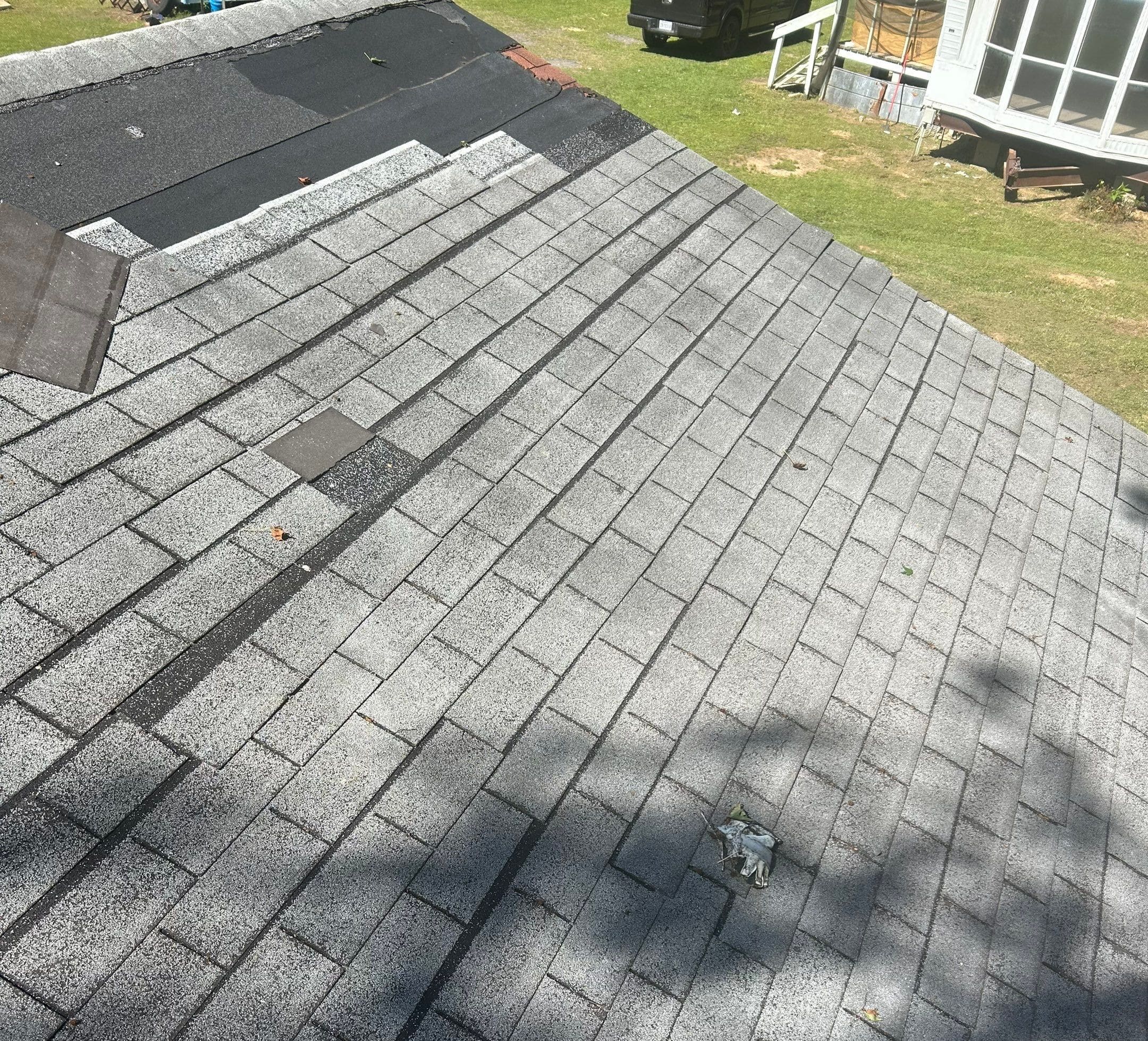 Worn asphalt shingle roof with a patched shingle and exposed underlayment needing leak repair in Shreveport