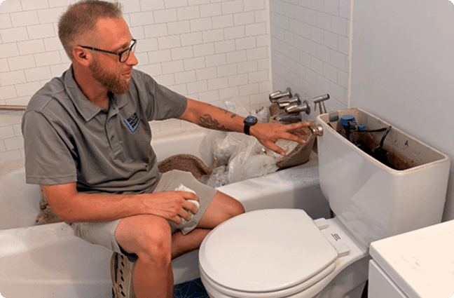Plumber repairing a toilet tank in a home bathroom
