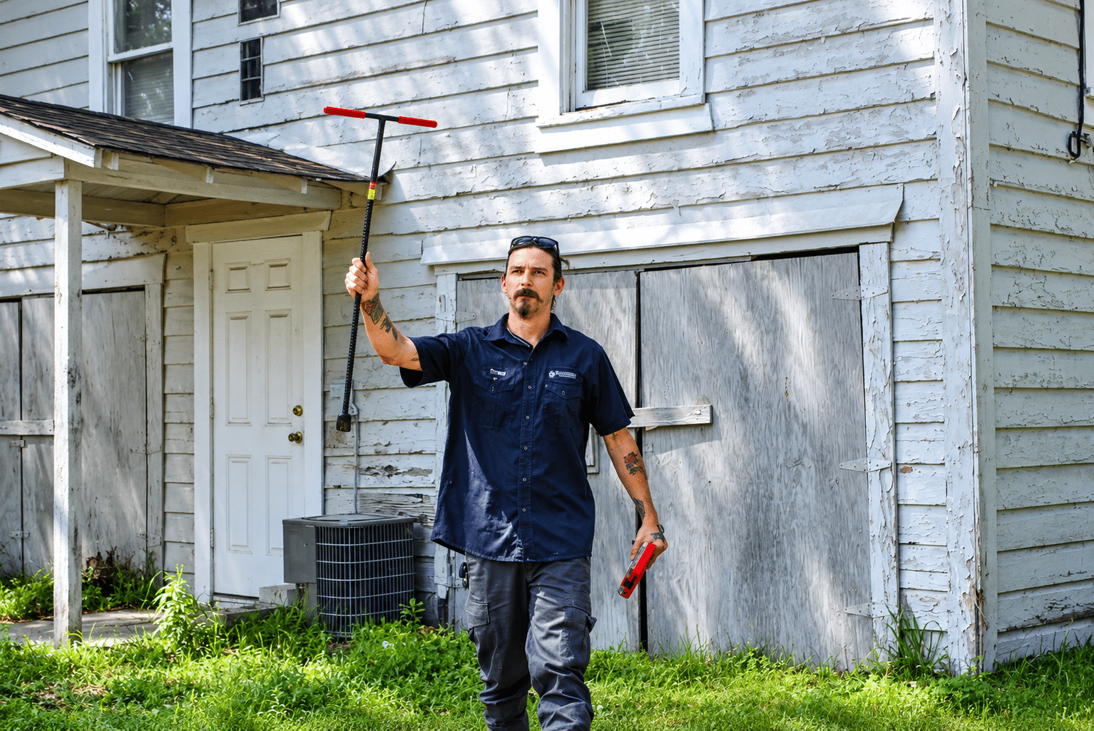 Blue Note Pros technician beside an outdoor AC condenser at a Shreveport home