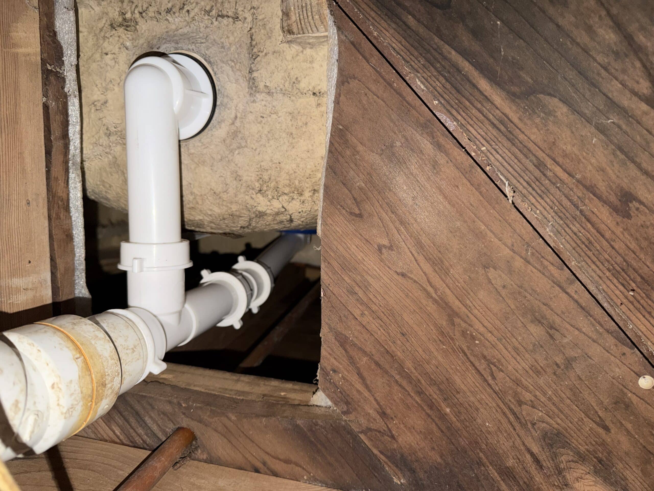 Exposed PVC drain pipes in a crawl space that should be insulated before freezing weather